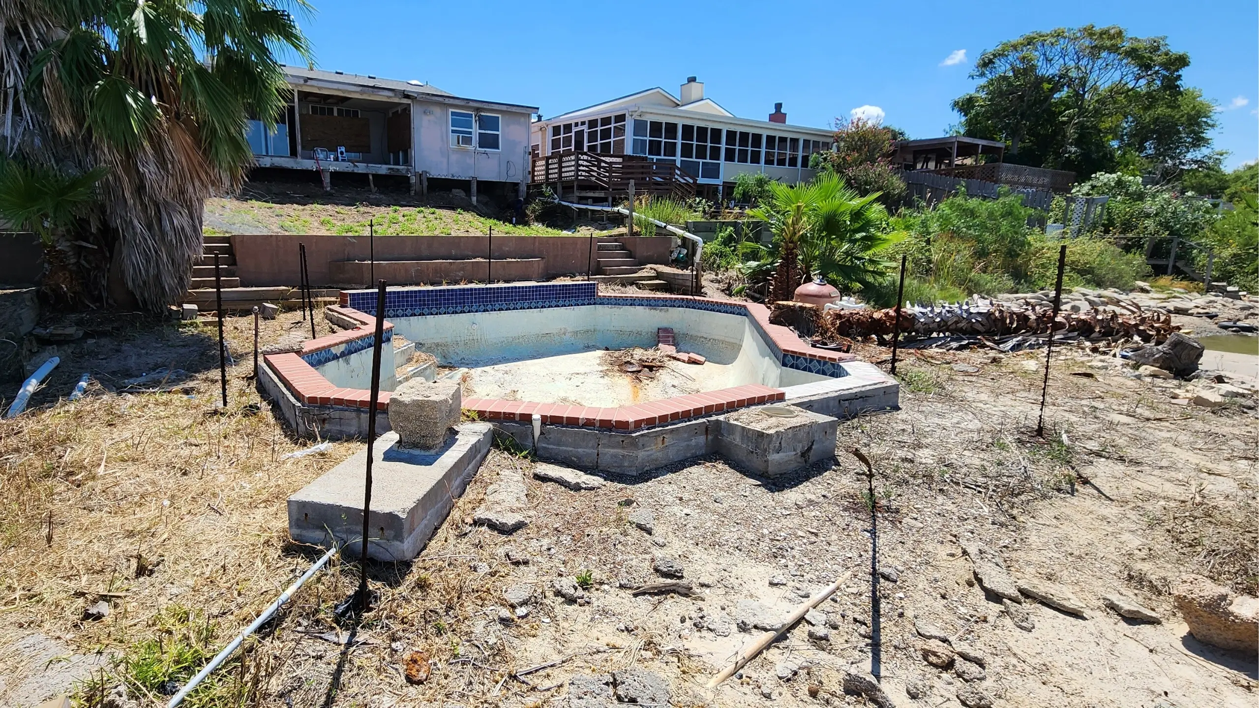 Turtle Cove - backyard before remodel with damaged pool, and broken barrier wall